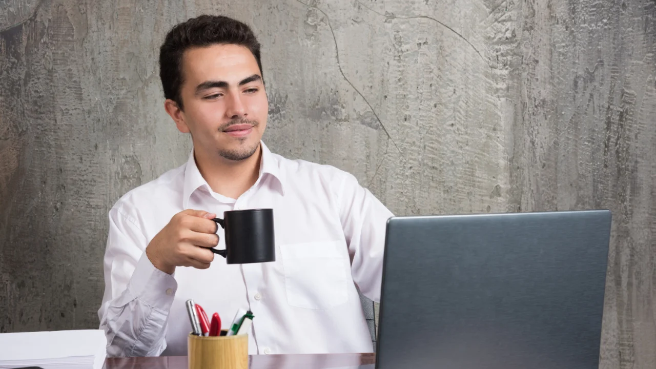 Atraer clientes a tu negocio: Hombre revisando su computador mientras toma café