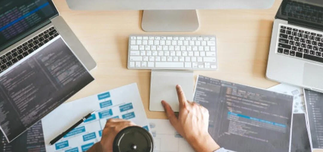 Diseño web: analizando gráfico y código en una mesa con dos computadores.